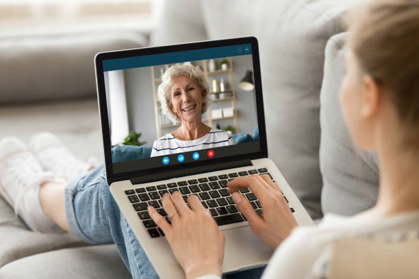 Lady on a remote video call on a laptop, with an older lady smiling on the screen.
